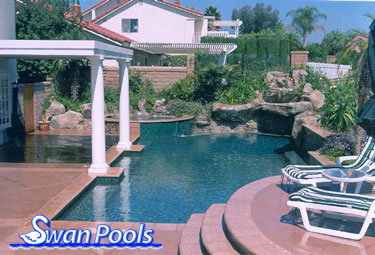Complete custom swimming pool construction project with artificial rock grotto by Swan Pools.