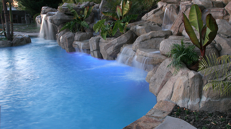 Modern swimming pool construction project in San Jose, California.  Sleek modern design in Silicon Valley with raised composite wood deck, concrete coping, stepping pads, smooth stucco veneered retaining wall and a Jandy/Zodiac sheer descent.  White interior quartz plaster.