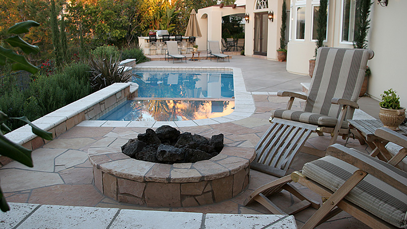 Swan Pools created this custom swimming pool interwined with the custom cottage in the wooded hills of Newport Beach, California.  Custom freestanding swimming pool and raised spa myander between the residence and pool house connected by a stone veneered, raised footbridge spanning the swimming pool and private cove.  Stone coping finishes the swimming pool well including, Caribbean Blue quartz plaster, led lighting, remote systems, and raised spa veneered in stone with custom width coping perfect for cool beachside evening entertaining. 