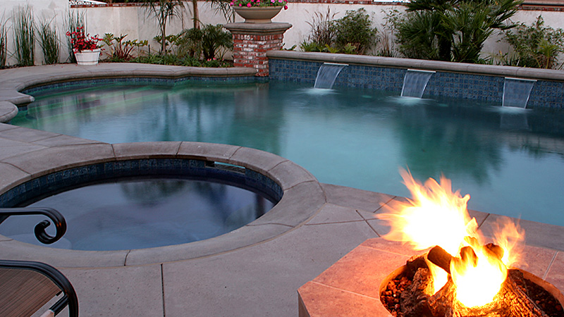 Modern swimming pool construction project in San Jose, California.  Sleek modern design in Silicon Valley with raised composite wood deck, concrete coping, stepping pads, smooth stucco veneered retaining wall and a Jandy/Zodiac sheer descent.  White interior quartz plaster.